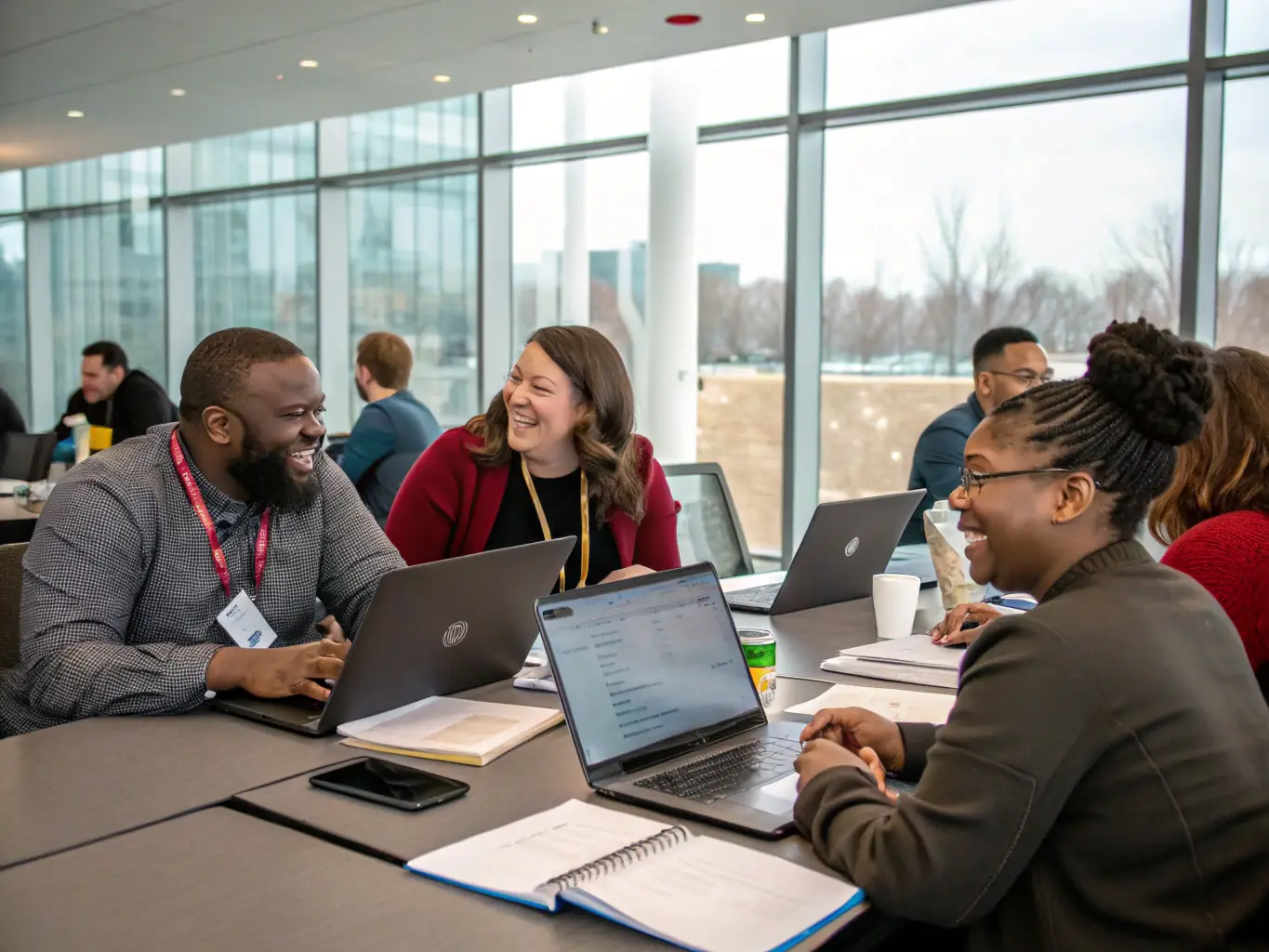 A photograph showing a group of conference attendees actively participating in a workshop session, with laptops open and engaging in discussions around a table.